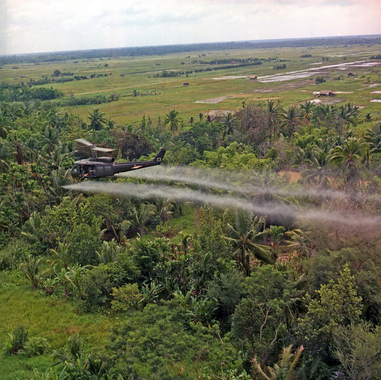 Een UH-1D helikopter van de 336th Aviation Company sproeit een ontbladeringsmiddel over een dicht junglegebied in de Mekong Delta, 26 juli 1969 door American Photographer
