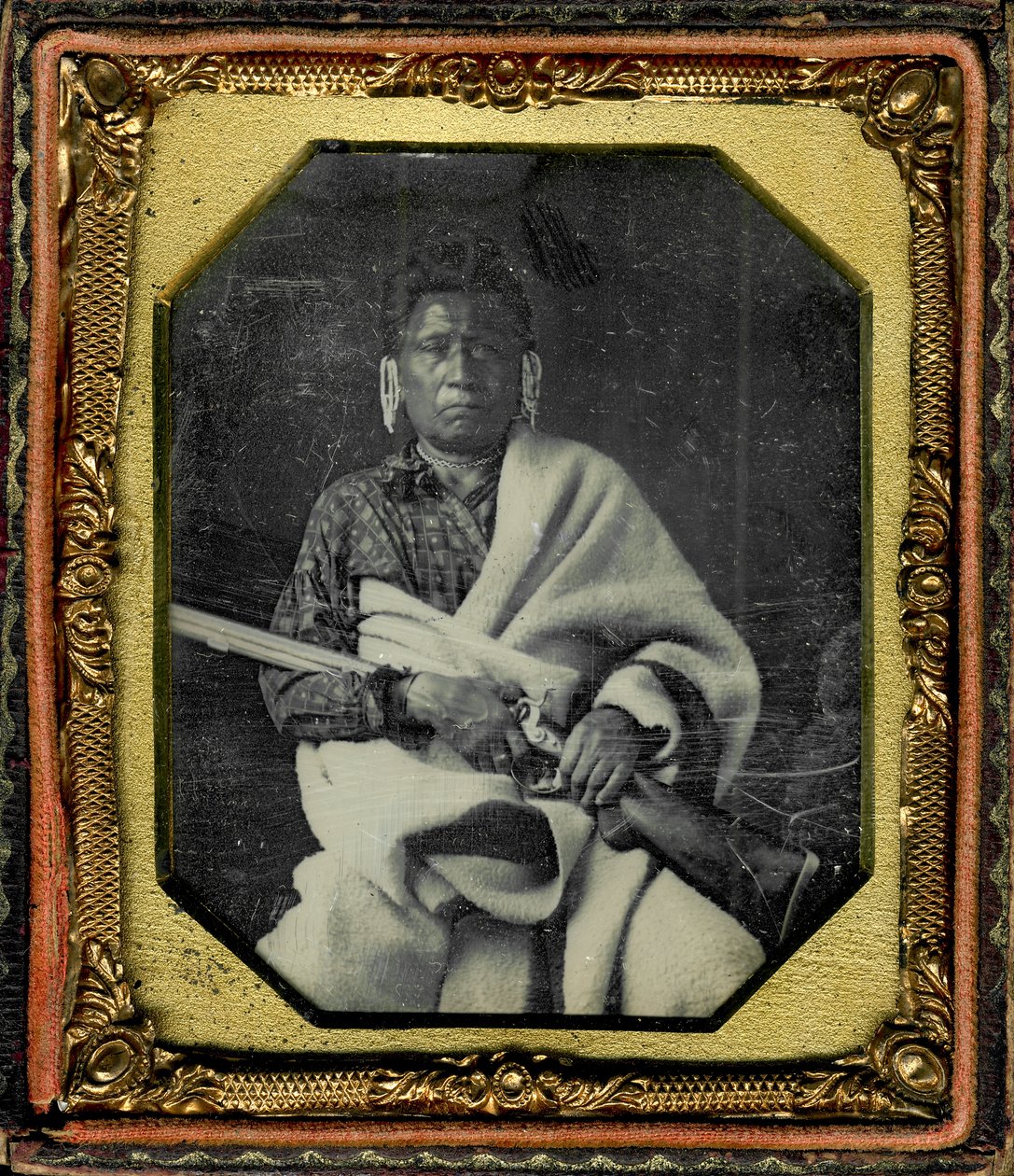 Portret van Nacheninga [No Heart of Fear], Iowa. Nacheninga houdt een geweer in zijn handen en is gewikkeld in een dikke deken door Thomas M. Easterly