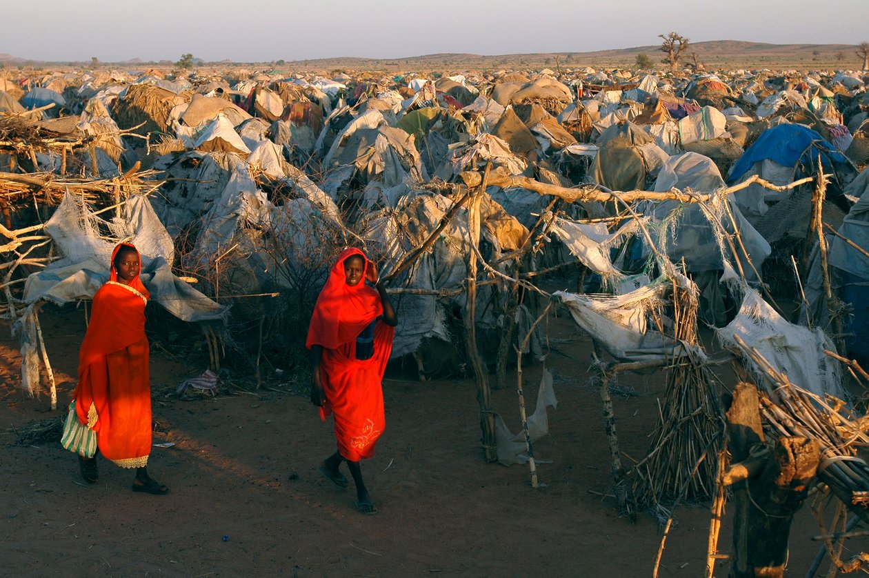 Gekleed in felrode kleren, lopen vrouwen door het Otash-kamp voor Intern Ontheemden door Unbekannt Unbekannt